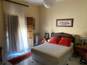 a bedroom with a bed with red pillows and a window at Casa Rural Oropesa in Villanueva del Ariscal