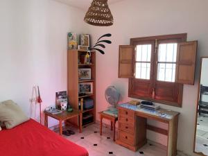 een slaapkamer met een bureau en een bed met een rode sprei bij Casa Rural Oropesa in Villanueva del Ariscal