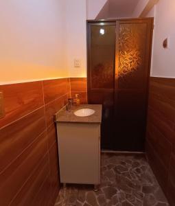 a bathroom with a sink and a black door at Hostal Casona Don Ranulfo in Peñas