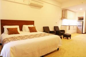 ネゴンボにあるOcean Breeze Apartment Negombo, R 5, B16 Minaのベッド1台と椅子2脚が備わるホテルルームです。