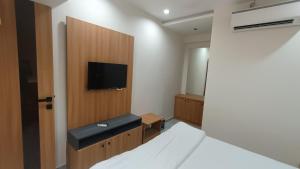 a bedroom with a bed and a tv on a wall at HOTEL RUBY in Adalaj