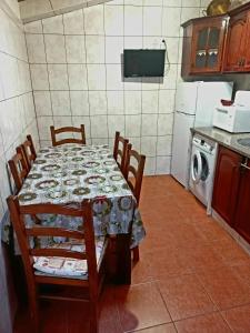 a kitchen with a table with chairs and a washing machine at O Refúgio dos Pais in Bordeira