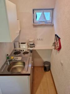 a small kitchen with a sink and a stove at gemütlicher Gartenbungalow (Nr. 1) mit Terrasse - Strandvogtei Sellin in Ostseebad Sellin