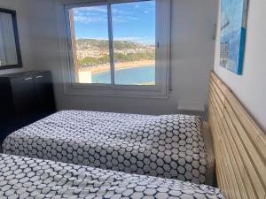 a bedroom with a bed with a view of a beach at Vue sur la baie de Sant Feliu de Guixols in Sant Feliu de Guíxols