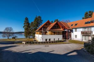 a large house with a lake in the background at Apartmán Andy Riviera 503-10 Lipno Home in Lipno nad Vltavou