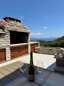 a bottle of wine and two glasses on a table at Kuća za odmor Samograd in Žrnovo