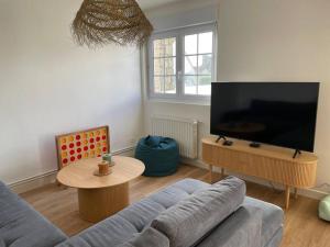 a living room with a couch and a flat screen tv at Jolie maison à Equihen-Plage in Équihen-Plage