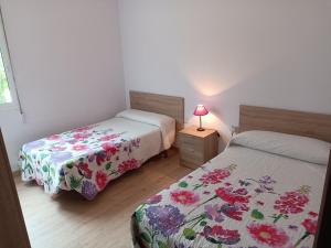 a bedroom with two beds and a table with a lamp at Pensión O Regato in Redondela