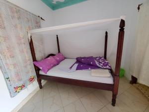 - un petit lit avec des oreillers violets dans l'établissement First Mayor' Garden, à Malamagambo