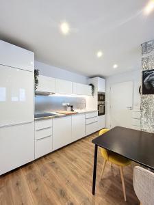 a kitchen with white cabinets and a black table at HYPERCENTRE, agréable T2 style LOFT , FIBRE in Grenoble