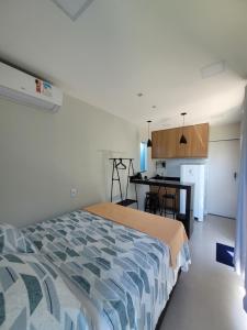 Un dormitorio con una cama y una cocina con una mesa. en Eco Loft Brisa do Mar, en Cabo Frío