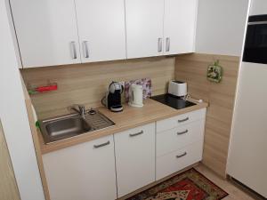 małą kuchnię z białymi szafkami i zlewem w obiekcie Apartament Bałtycka 6B w Kołobrzegu