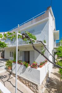 a white house with potted plants in front of it at Apartments Nikola Stipišić in Hvar