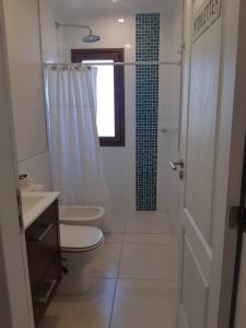 a white bathroom with a toilet and a shower at Hermosa casa en barrio privado de 2 habitaciones in Concepción del Uruguay