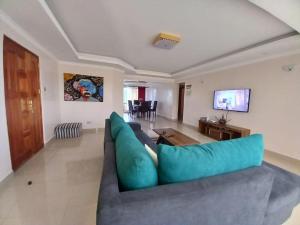 sala de estar con sofá azul y TV en FH apartments opposite culture mambo en Nakuru