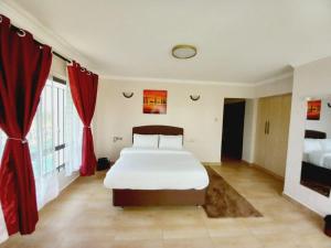 a bedroom with a large bed and red curtains at FH apartments opposite culture mambo in Nakuru