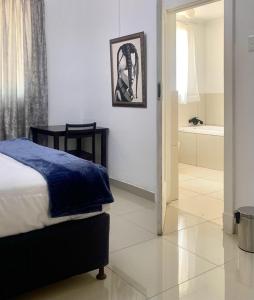 a bedroom with a bed and a bathroom with a tub at Khaya Mnandi Leisure Suites in Pretoria