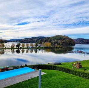 een uitzicht op een meer met een zwembad bij L57_resort in Gródek Nad Dunajcem
