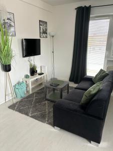 a living room with a black couch and a table at Apartament Sobieskiego in Zabrze