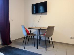 einen Tisch mit 2 Stühlen und einen TV an der Wand in der Unterkunft Simplex Apartments Am Europaplatz in Karlsruhe