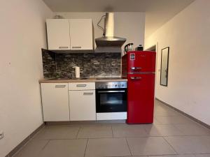 um frigorífico vermelho numa cozinha com armários brancos em Simplex Apartments Am Europaplatz em Karlsruhe