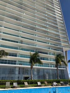 a large building with palm trees in front of it at Departamento de Lujo Vista al mar Piso 15 in Mazatlán