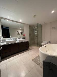 a bathroom with two sinks and a tub and a shower at Departamento de Lujo Vista al mar Piso 15 in Mazatlán