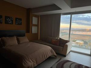 a bedroom with a bed and a couch and a large window at Departamento de Lujo Vista al mar Piso 15 in Mazatlán +14 photos