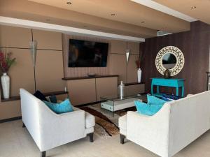 a living room with two white chairs and a table at Departamento de Lujo Vista al mar Piso 15 in Mazatlán