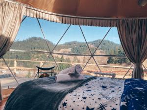 a bedroom with a bed and a large window at Cazare Dom Pensiuni Vatra Dornei Bucovina cu Ciubar in Iacobeni