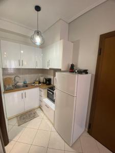 cocina con armarios blancos y nevera blanca en cozy apartment en Volos