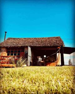 uma casa velha com um campo de relva em frente em Quincho Nativo em Tacuarembó