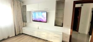 uma sala de estar com televisão numa parede branca em Brancoveanu Apartament's em Bucareste