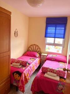 een slaapkamer met 2 bedden met roze lakens en een raam bij Apartamento en la Playa Canet, muy cerca de Valencia in Canet de Berenguer