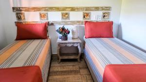 two beds with red pillows in a room with a table at Mirante de Lençóis in Lençóis
