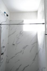 La salle de bains blanche est pourvue d'une porte de douche en verre. dans l'établissement Departamento eco-chic a 10 min del centro, à Tulum