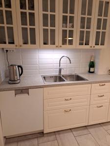 a kitchen with white cabinets and a sink at Lägenhet på Rosenlund in Jönköping