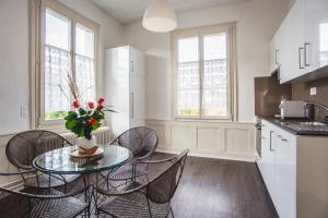 - une cuisine avec une table en verre, des chaises et des fenêtres dans l'établissement Auberge d'Ajoie, à Porrentruy