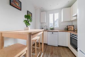 eine Küche mit weißen Schränken und einem Holztisch in der Unterkunft Spacieux 2 Chambres Appart Boulogne-Quai in Boulogne-Billancourt