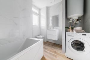 ein weißes Badezimmer mit einer Waschmaschine und einem Waschbecken in der Unterkunft Spacieux 2 Chambres Appart Boulogne-Quai in Boulogne-Billancourt