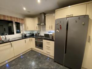 una cocina con nevera de acero inoxidable y armarios blancos en Richard's Home, en Kidderminster