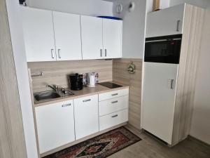 kuchnia z białymi szafkami, zlewem i lodówką w obiekcie Apartament Bałtycka 6B w Kołobrzegu