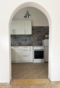 a kitchen with white appliances and an archway at Ariadni's home - Einfamilienhaus mit Meerblick in Nea Stira