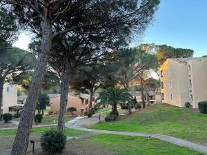 un parque con árboles y un edificio y una calle en Domaine Valescure Appartement 1 ou 2 pieces vue jardin ou piscine en Saint-Raphaël