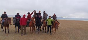 grupa ludzi jeżdżących konno na plaży w obiekcie Son-Kul Northen yurt camp w mieście Kochkorka