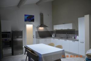 une cuisine avec des armoires blanches et une table avec des chaises dans l'établissement LA BAMBOUSERAIE, à Saint-Rémy-de-Provence