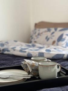 a tray with plates and a coffee cup on a bed at Koslig bolig med sjøutsikt in Asker