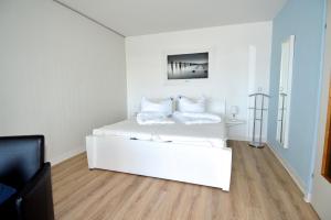 ein weißes Schlafzimmer mit einem weißen Bett und weißen Kissen in der Unterkunft Ferienpark Hs N Etage 8 Whg 2 in Heiligenhafen