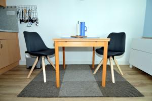 einen Holztisch mit zwei schwarzen Stühlen neben einer Küche in der Unterkunft Ferienpark Hs N Etage 8 Whg 2 in Heiligenhafen