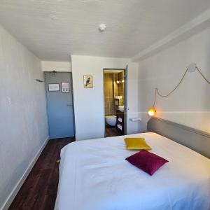 una camera da letto con un grande letto bianco con un cuscino giallo di Hôtel Candide a Saint-Bertrand-de-Comminges